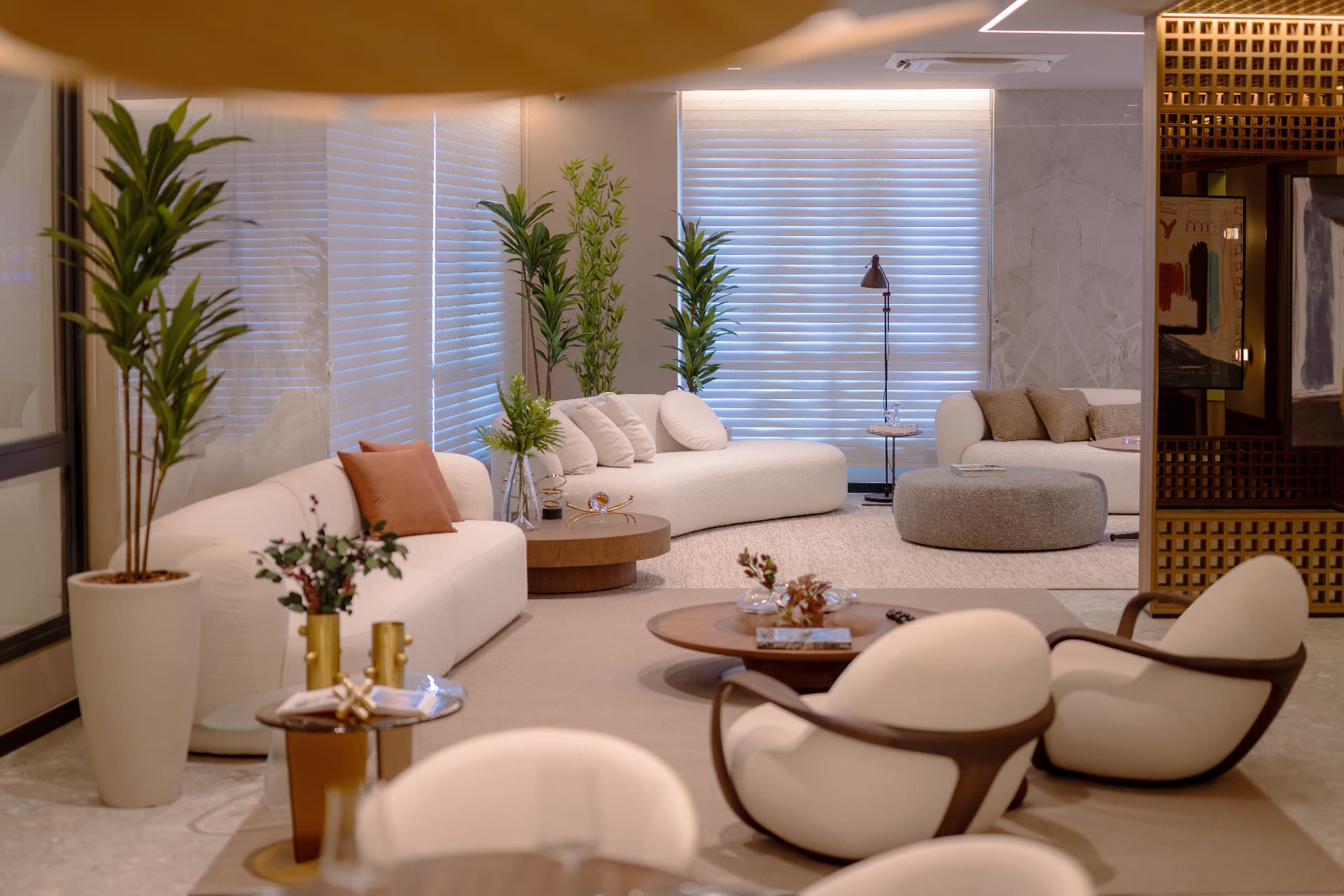 Salão de estar decorado com poltronas claras e plantas